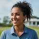 A smiling woman with dark hair, wearing a light blue athletic top, poses for a candid headshot against a softly blurred backg